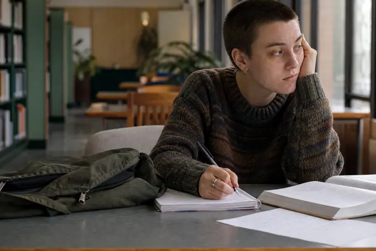 A person at a sunlit desk placing a phone face down and opening a notebook to one simple task.