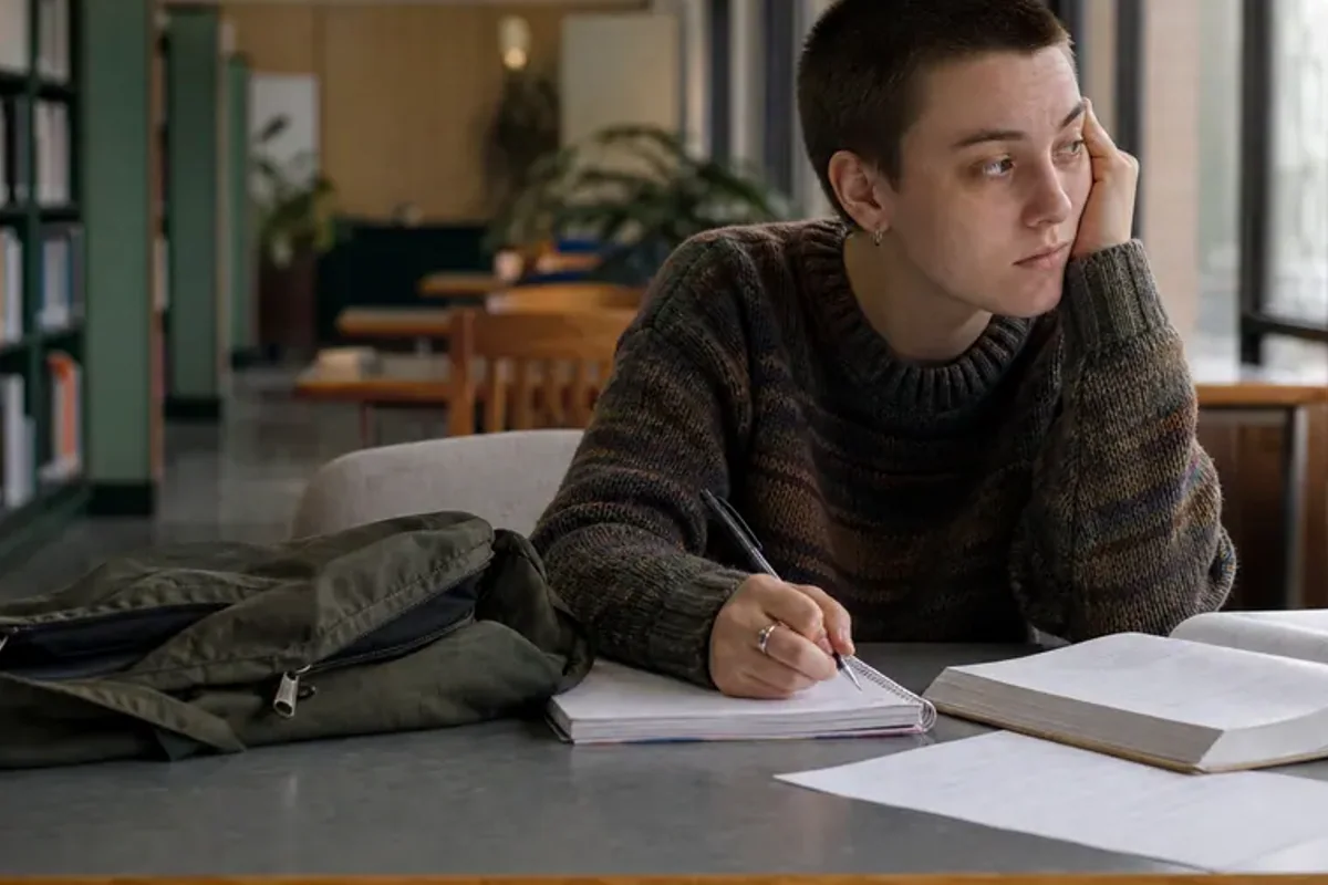 A person at a sunlit desk placing a phone face down and opening a notebook to one simple task.