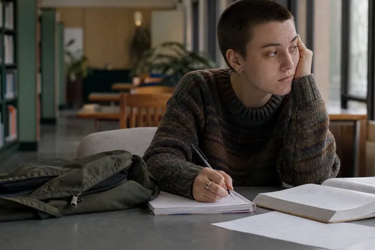 A person at a sunlit desk placing a phone face down and opening a notebook to one simple task.