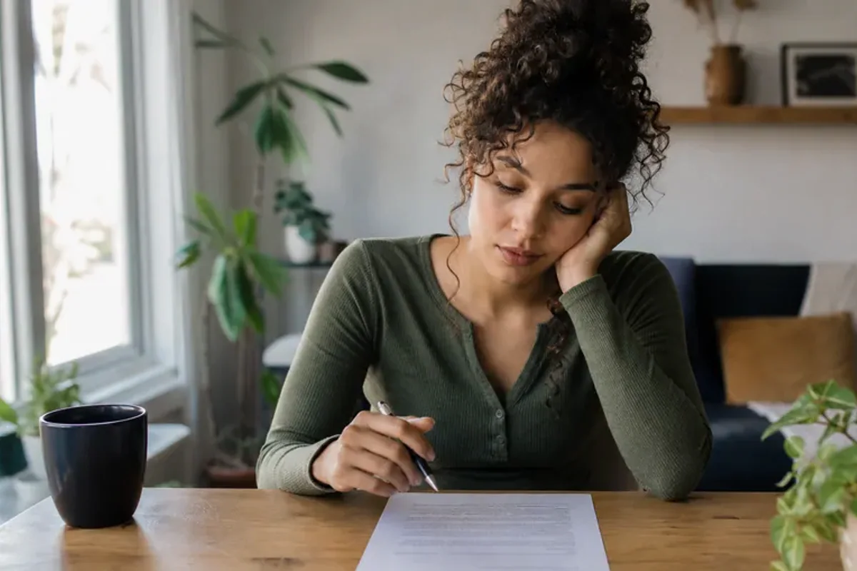 A person at a sunlit desk placing a phone face down and opening a notebook to one simple task.