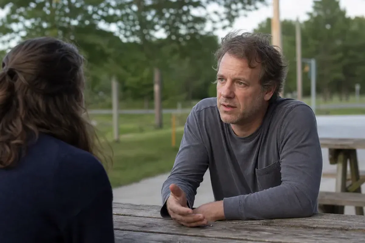 Two friends talking on a quiet park bench with attentive, unforced body language.