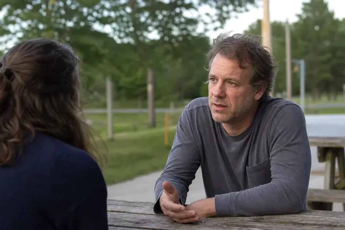 Two friends talking on a quiet park bench with attentive, unforced body language.