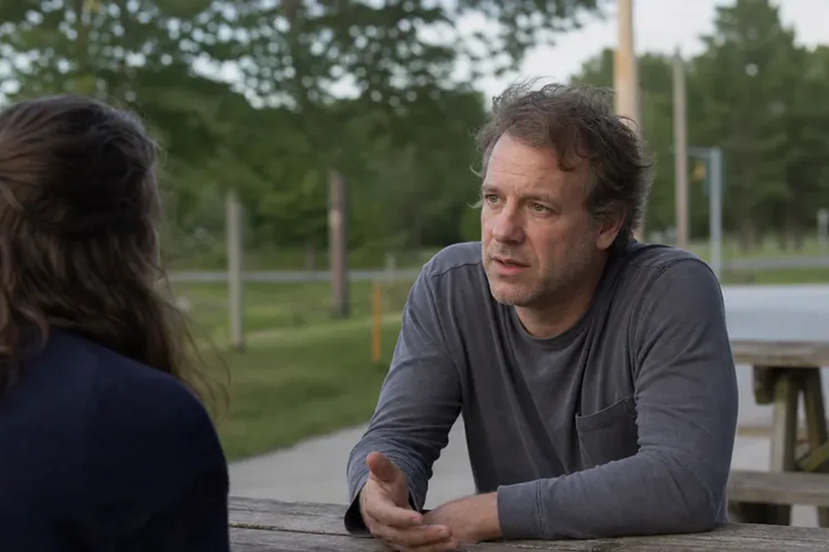 Two friends talking on a quiet park bench with attentive, unforced body language.