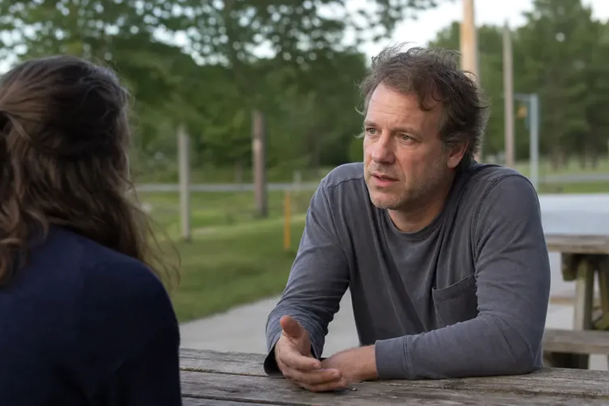 Two friends talking on a quiet park bench with attentive, unforced body language.