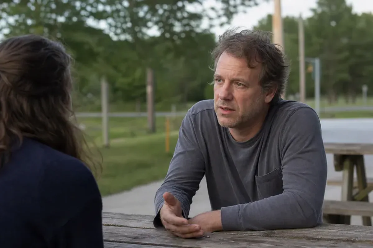 Two friends talking on a quiet park bench with attentive, unforced body language.