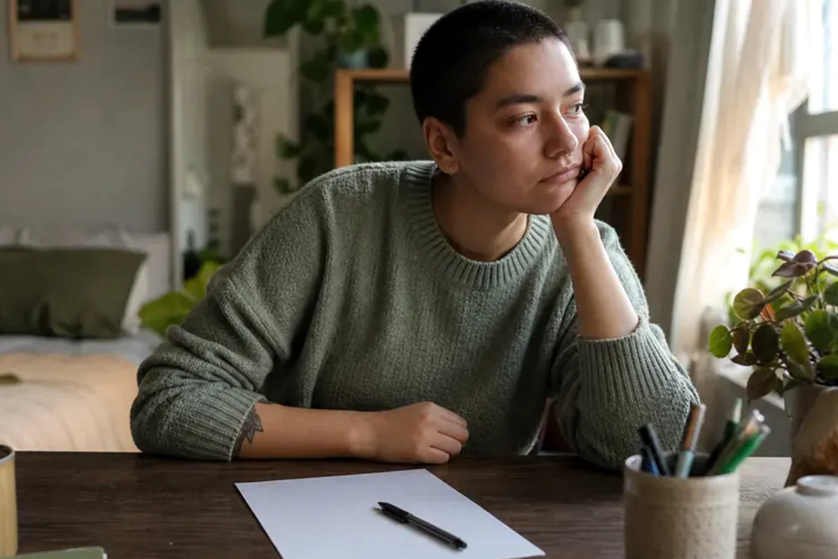 A person at a sunlit desk placing a phone face down and opening a notebook to one simple task.