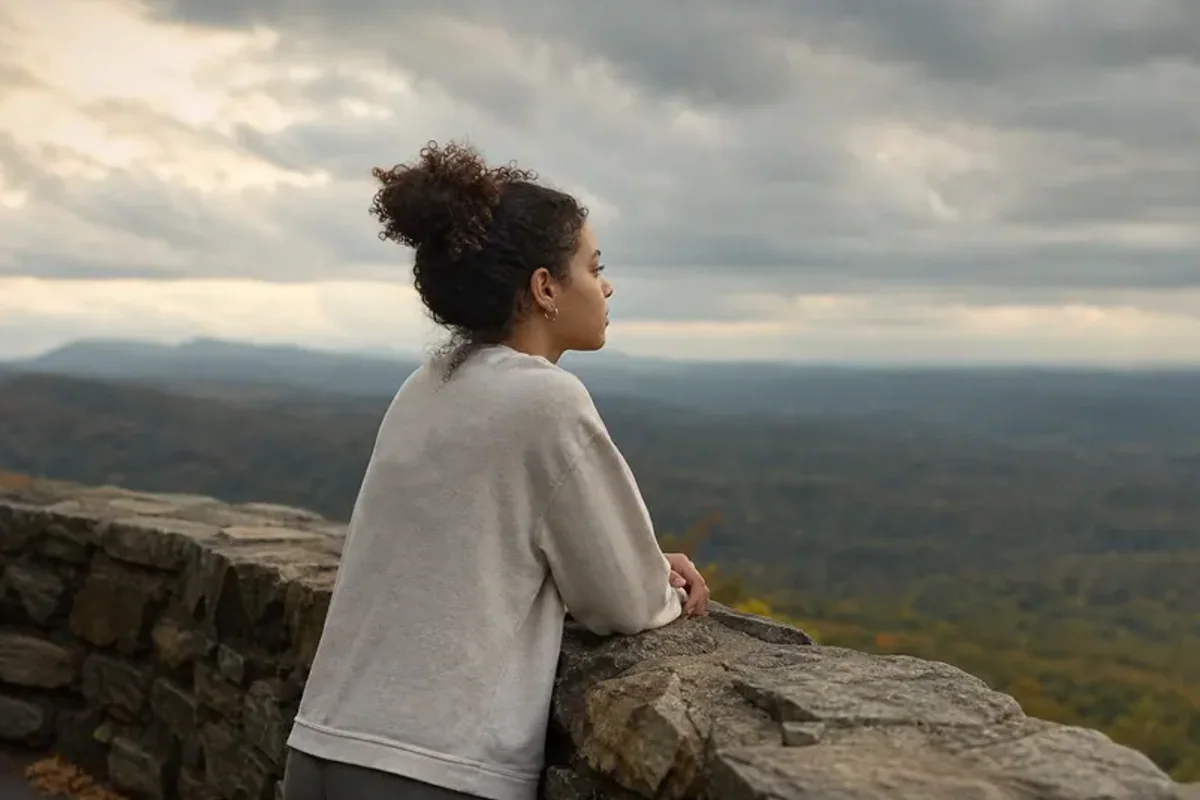 A person looking across a wide, misty landscape from a safe overlook at early morning.