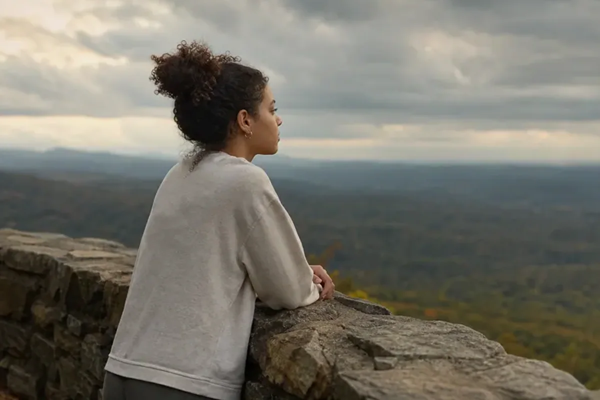 A person looking across a wide, misty landscape from a safe overlook at early morning.