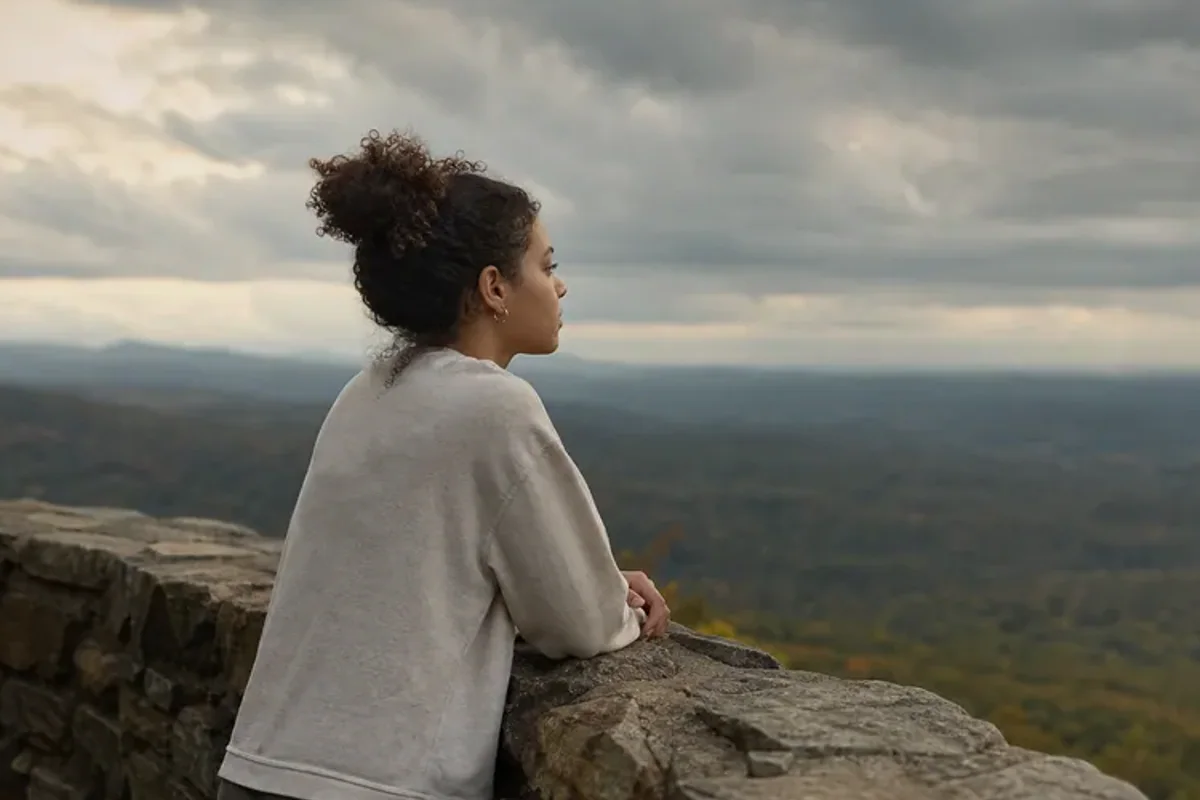 A person looking across a wide, misty landscape from a safe overlook at early morning.