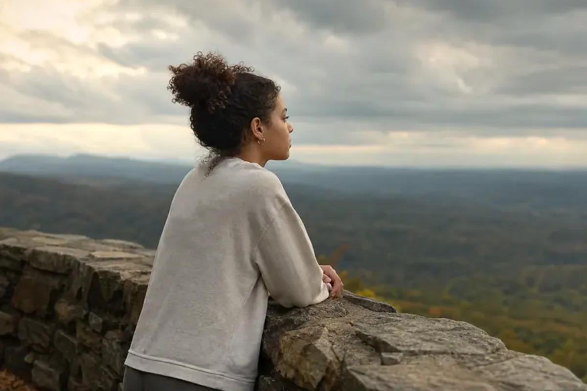A person looking across a wide, misty landscape from a safe overlook at early morning.