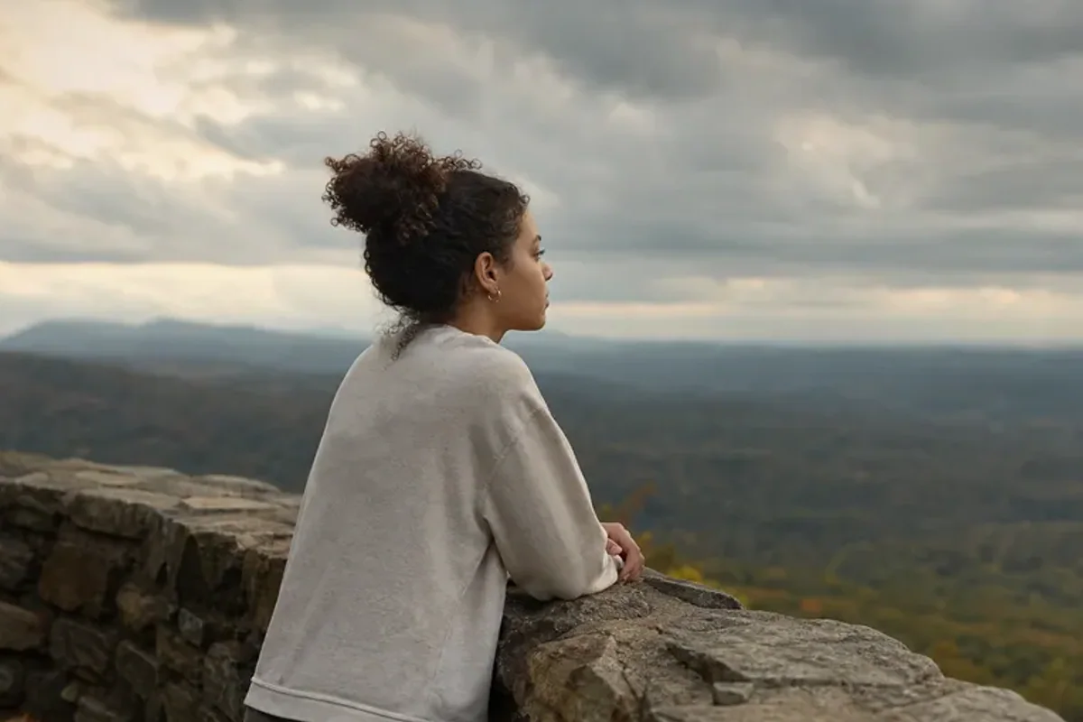 A person looking across a wide, misty landscape from a safe overlook at early morning.