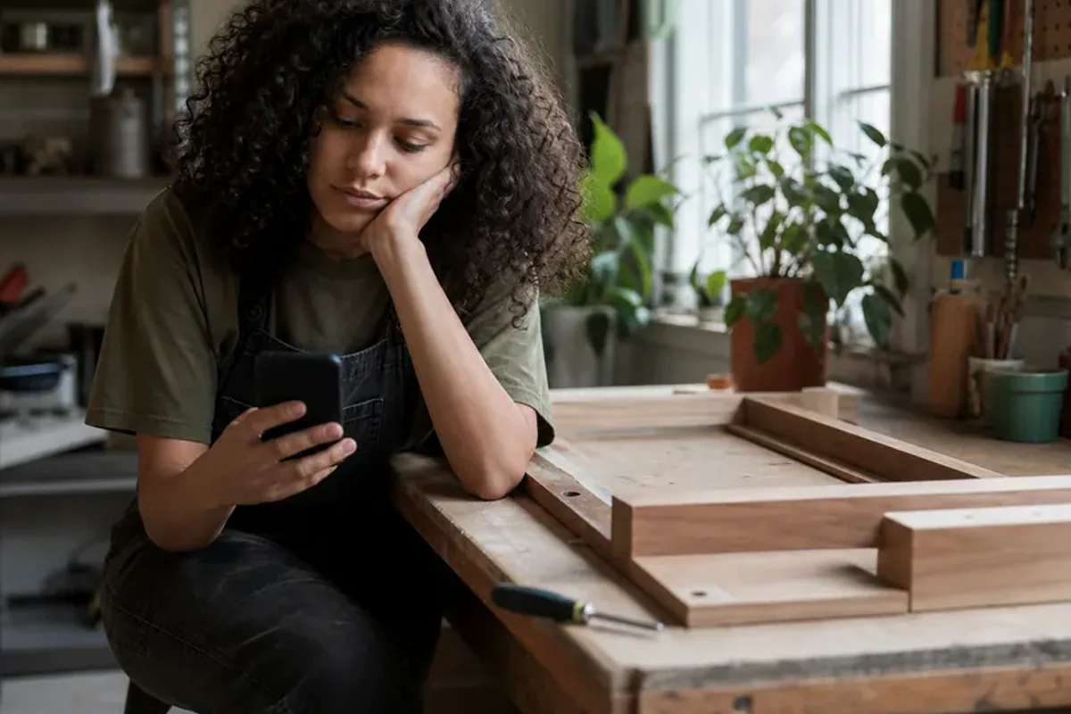 A person at a sunlit desk placing a phone face down and opening a notebook to one simple task.