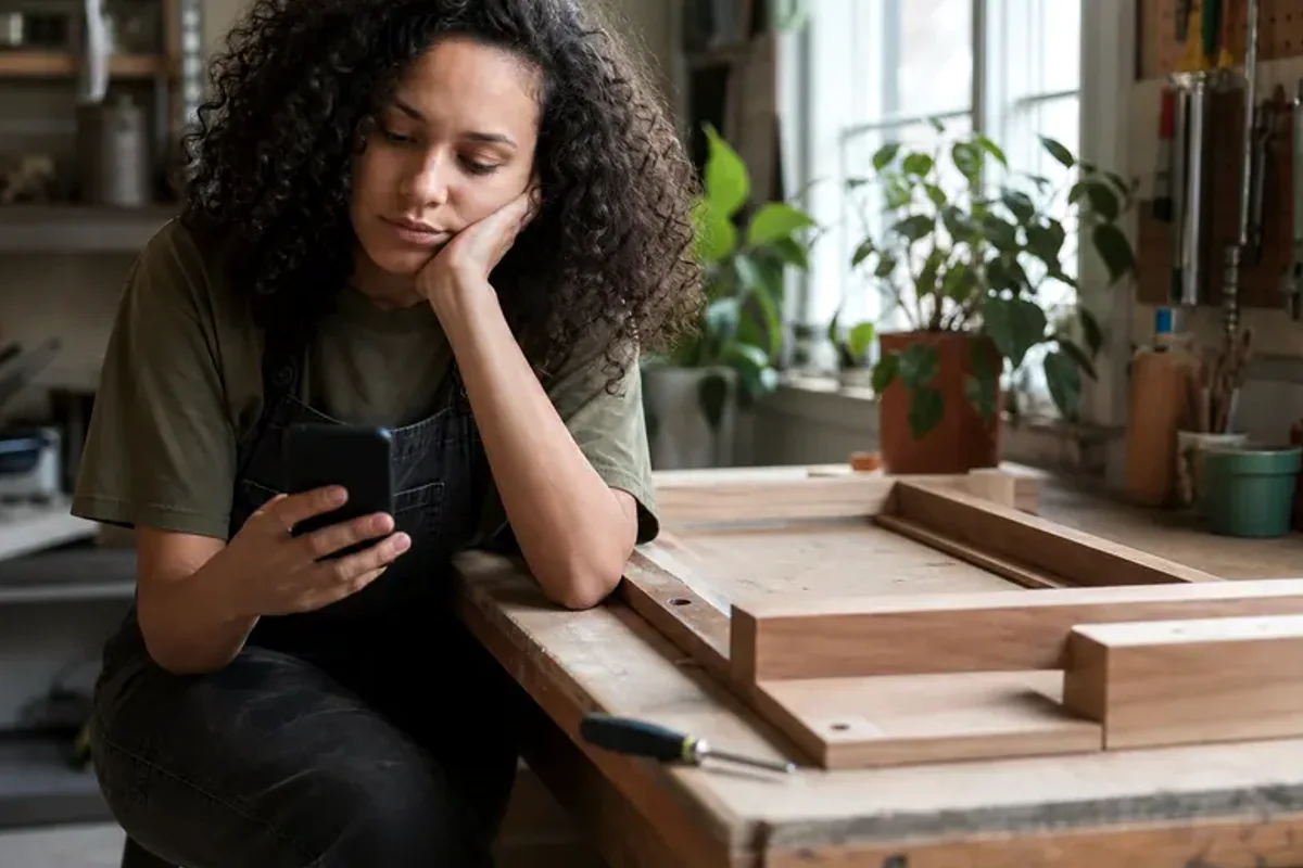 A person at a sunlit desk placing a phone face down and opening a notebook to one simple task.