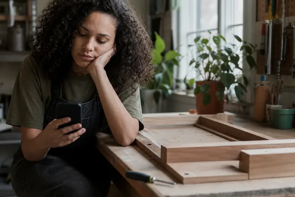A person at a sunlit desk placing a phone face down and opening a notebook to one simple task.