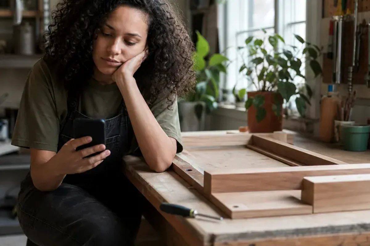 A person at a sunlit desk placing a phone face down and opening a notebook to one simple task.