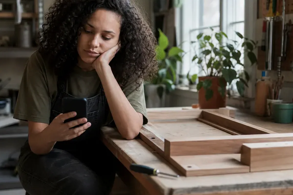 A person at a sunlit desk placing a phone face down and opening a notebook to one simple task.