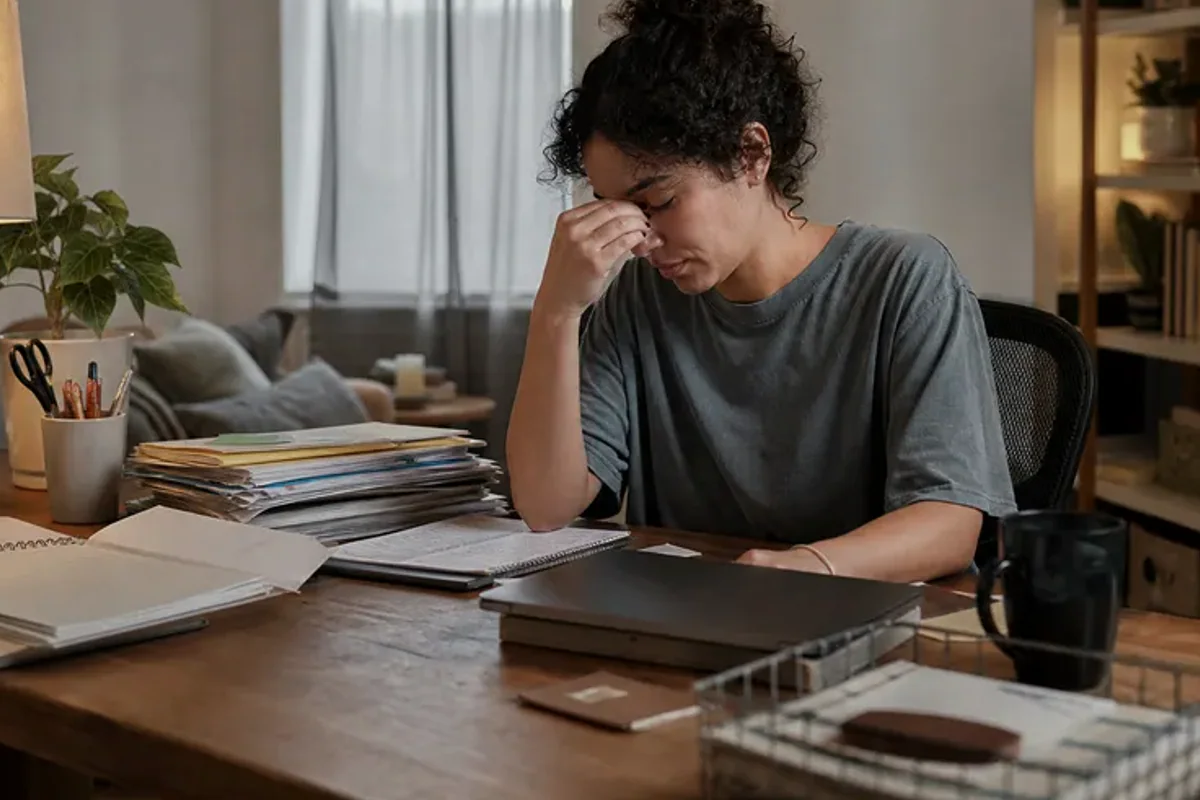 A person standing by a bright window, resting one hand lightly near the chest and noticing a slow breath.